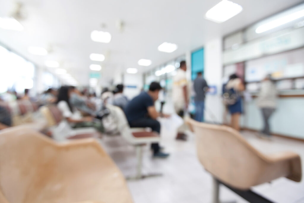 Blurred photo of several patients in a hospital waiting room.
