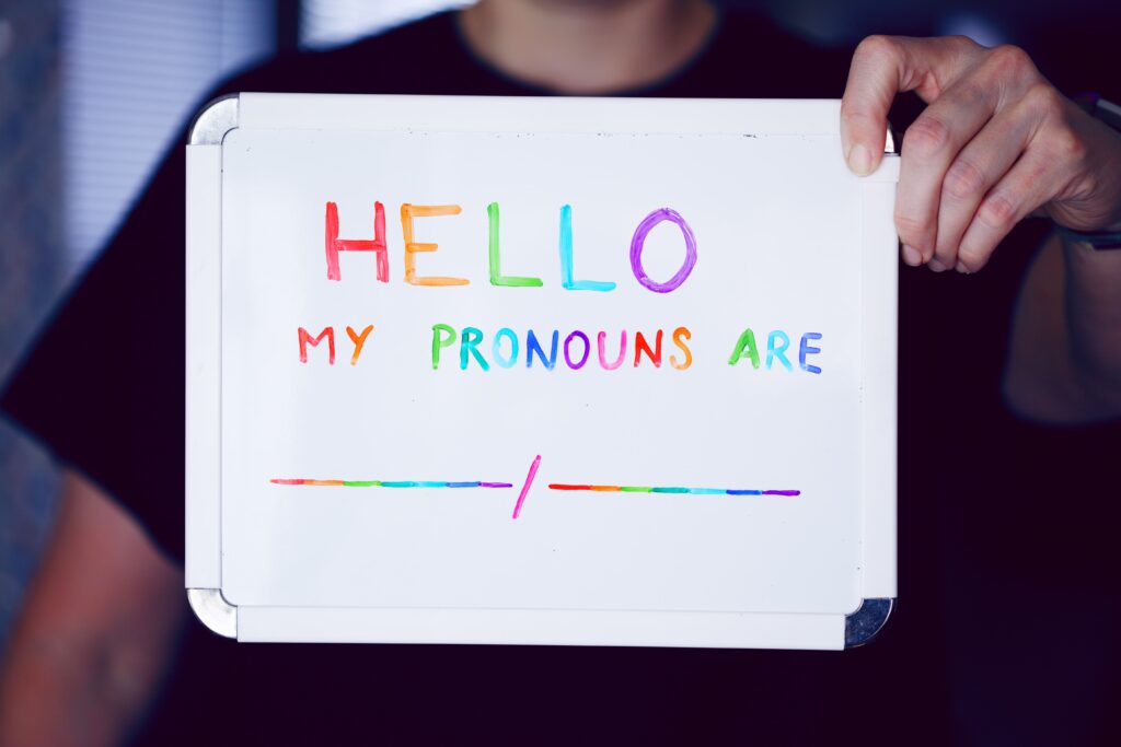 Someone holding a whiteboard sign that reads 'Hello. My pronouns are…'
