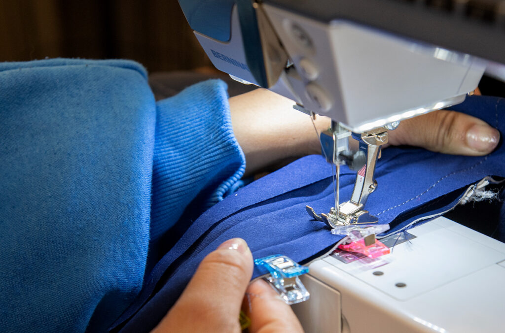 Closeup of someone's hands guiding fabric through a sewing machine.