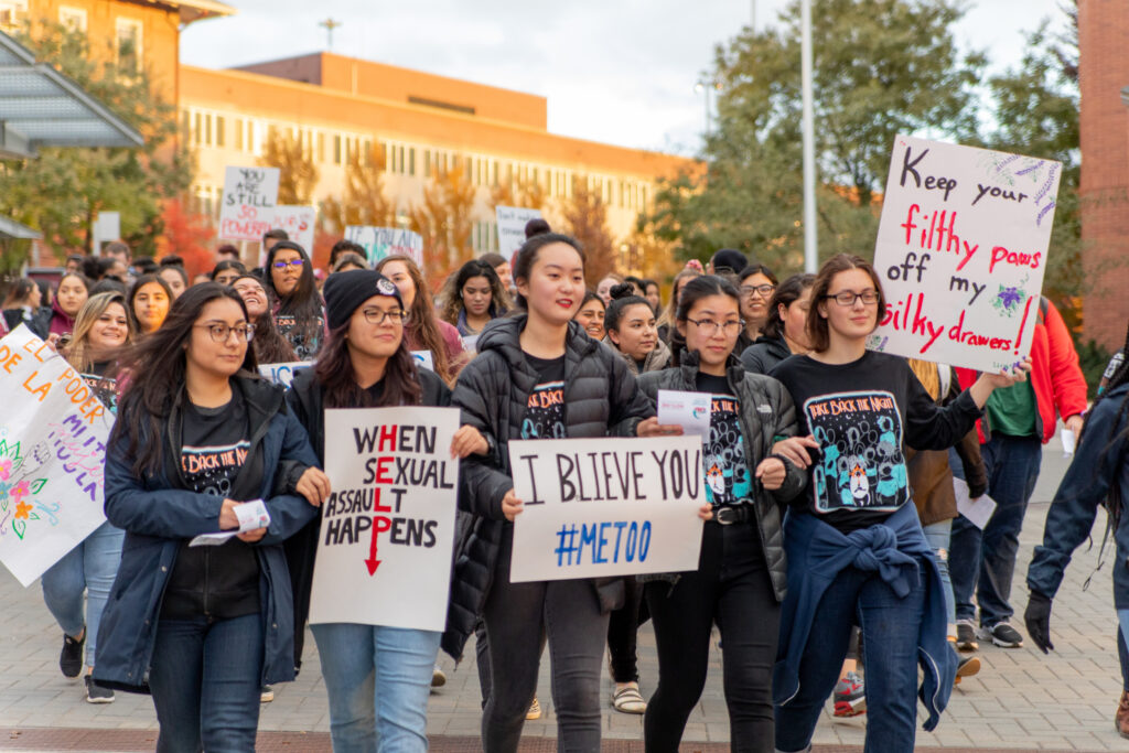 Students holding signs as they march across the WSU Pullman campus during Take Back the Night.