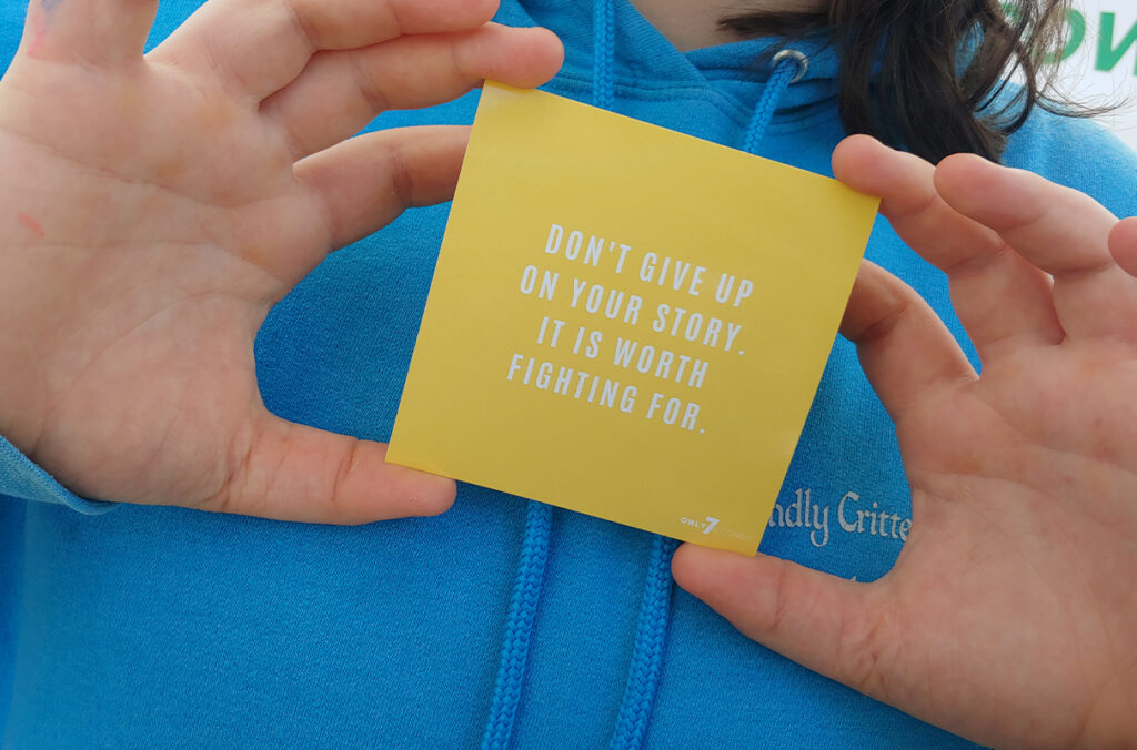 Person holding a card that reads, "Don't give up on your story. It is worth fighting for."