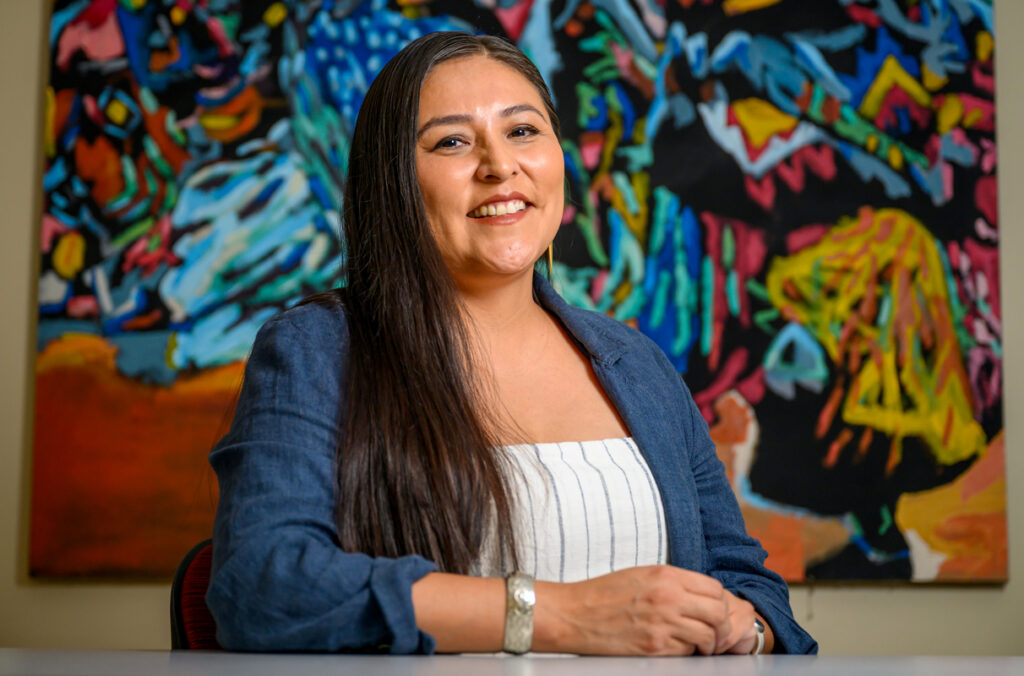 Cheryl Ellenwood sitting in front of a painting.
