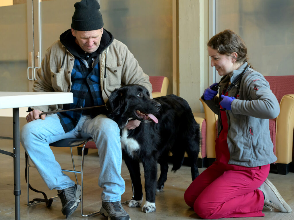 Chloe Hoover kneels as she prepares to examine Sampson's dog, Rambo.