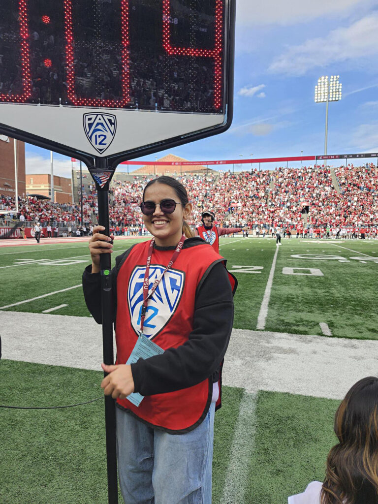Sneha Kataria holding the "victory clock" on the sideline of a WSU football game.