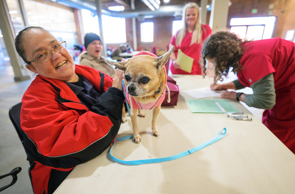 Serena Simmons sitting at a table with her pug-chihuahua mix dog, Sharon.