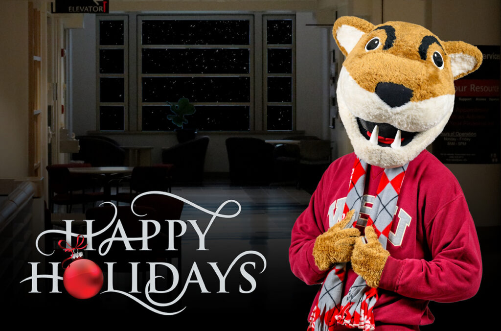 Butch T. Cougar standing in an empty hallway with the words Happy Holidays.
