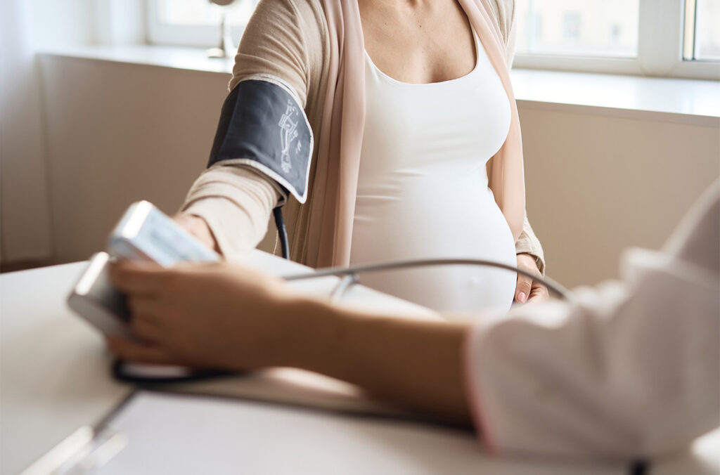 A pregnant woman getting her blood pressure taken by a doctor.