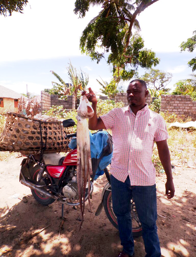 A man holding an octopus being sold in the local fish market.
