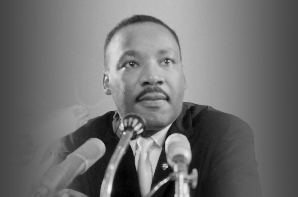 Martin Luther King, Junior sitting in front of several microphones.
