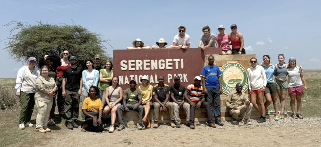 Students gathered for a group photo in front of a sign for Serengeti National Park.