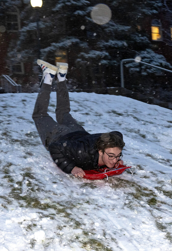A WSU Pullman student sledding head first with his feet in the air.