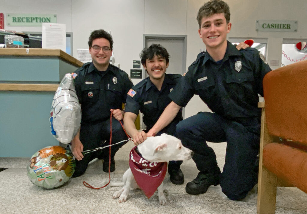 Three firefighters pose for a photo with a dog that they rescued from a house fire.