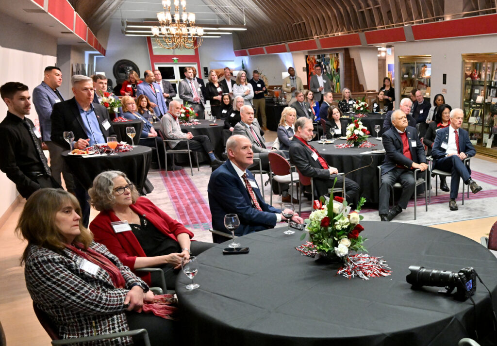 Tables and chairs full of attendees listening to someone speaking.