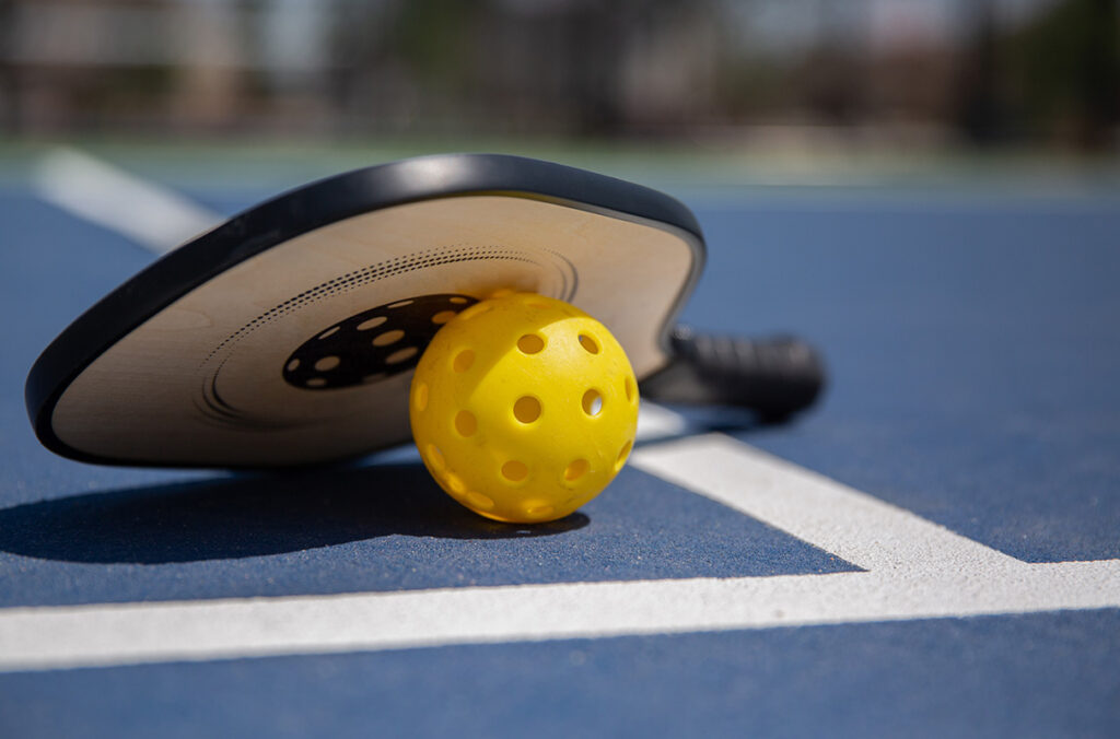 Closeup of a pickleball ball and paddle.