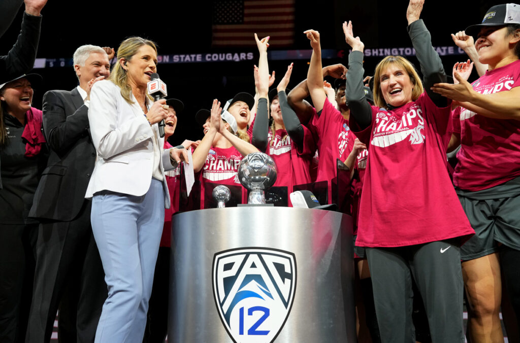 The WSU women’s basketball team celebrating next to the Pac-12 championship trophy.