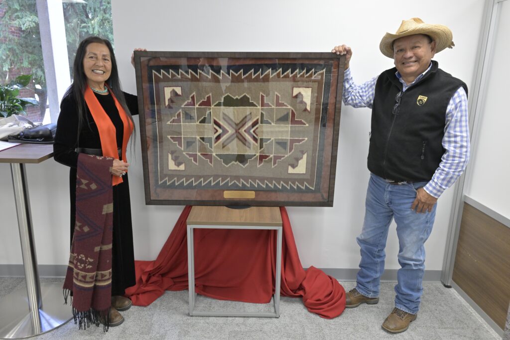 Joseph Bahe and Alberta Arviso pose next to a traditional Navajo rug.