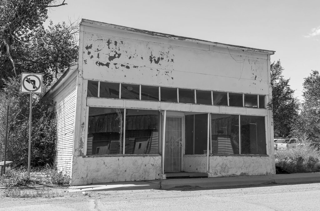 A black and white image of an abandoned storefront in a small town.