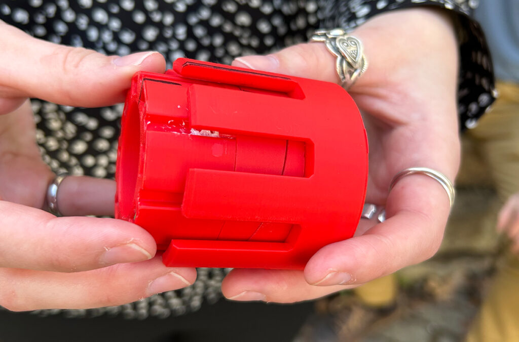 Closeup of hands holding a prototype of a coupler that WSU students are developing as part of a NASA competition.