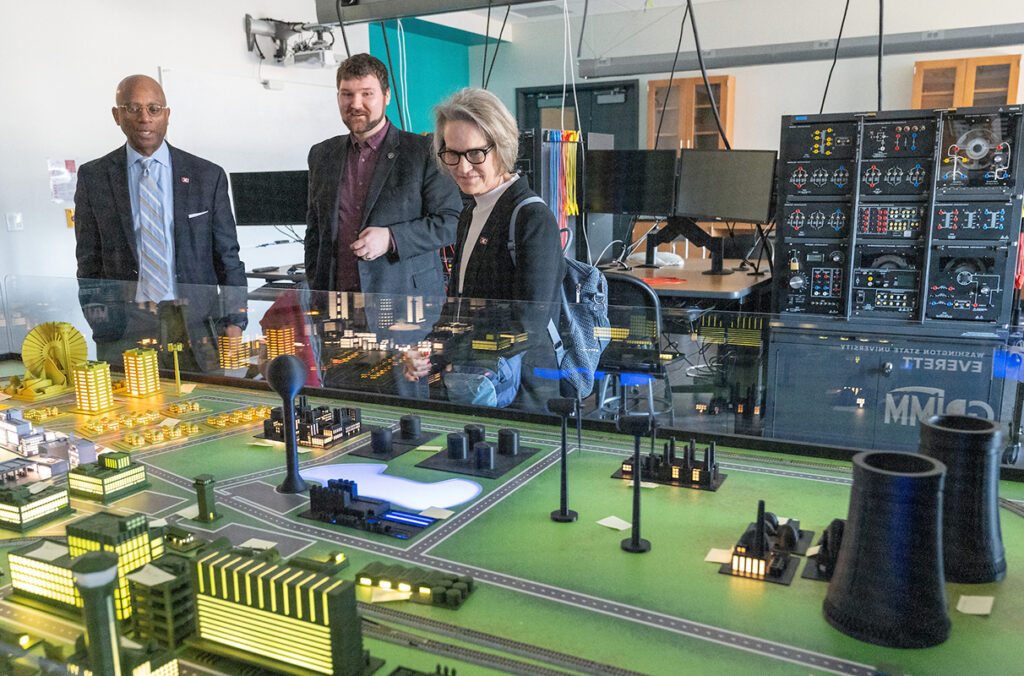 WSU President Elizabeth Cantwell looking at a model of illuminated homes, businesses, and factories.