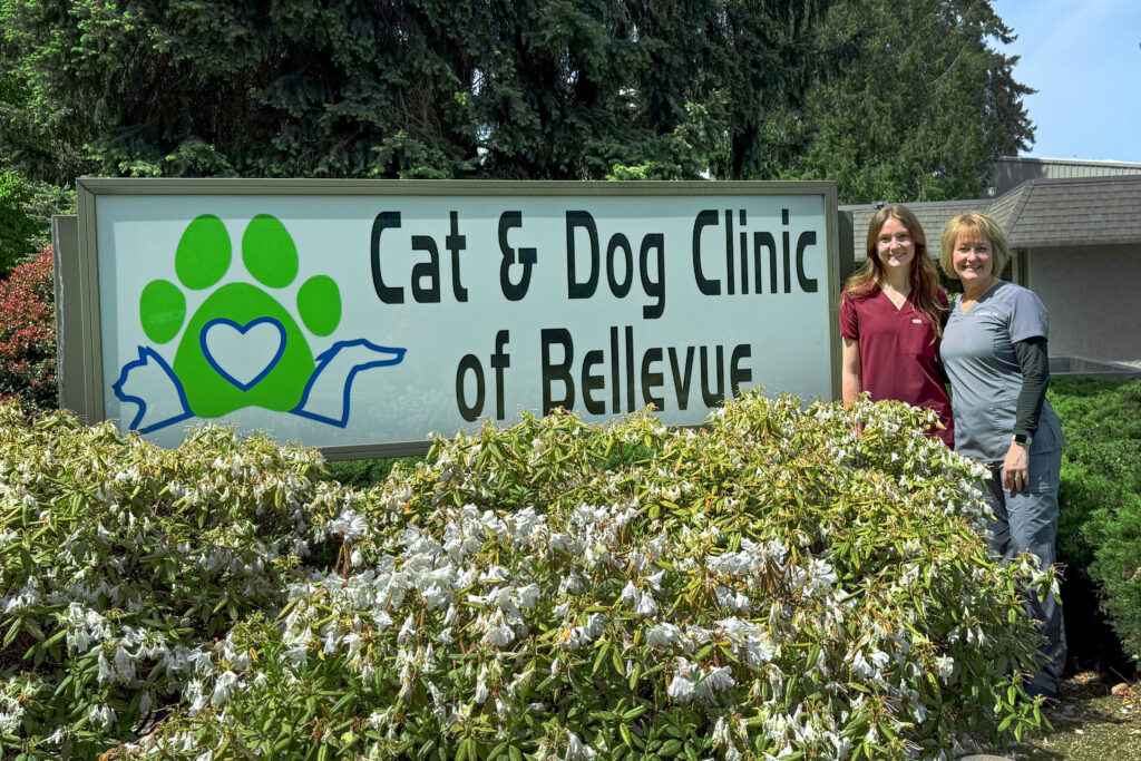 Tori Wallingford posing with her mother, Debora Wallingford, next to a sign for the Cat & Dog Clinic of Bellevue.