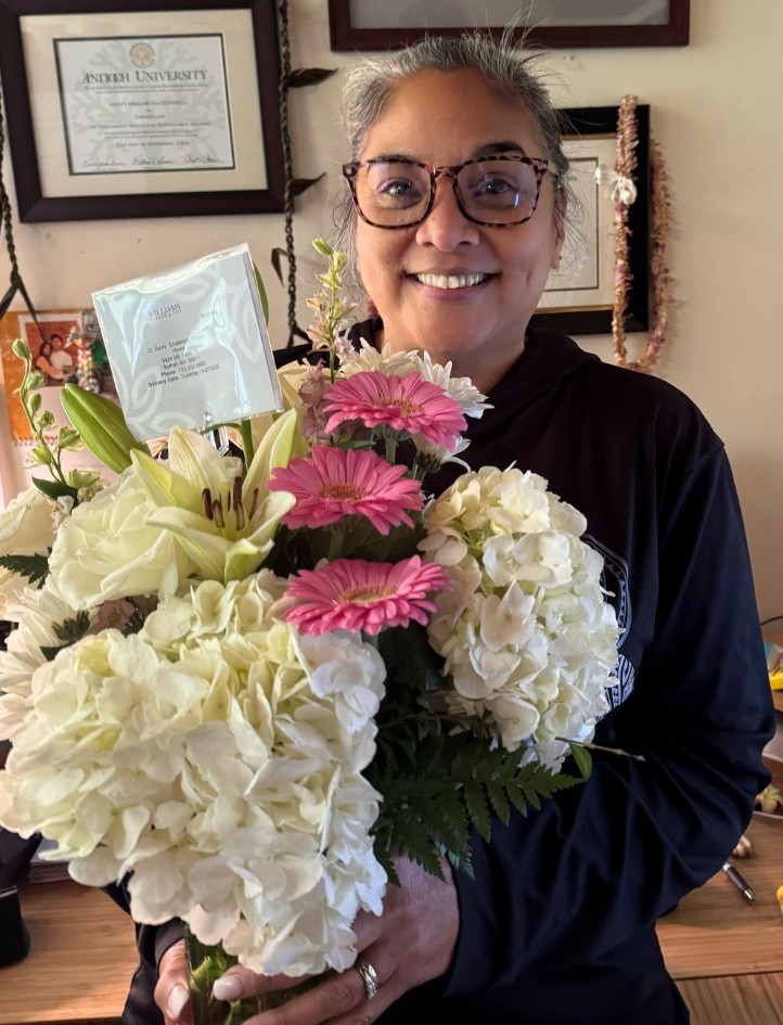 Gerry Ebalaroza-Tunnell holding a bouquet of pink and white flowers.