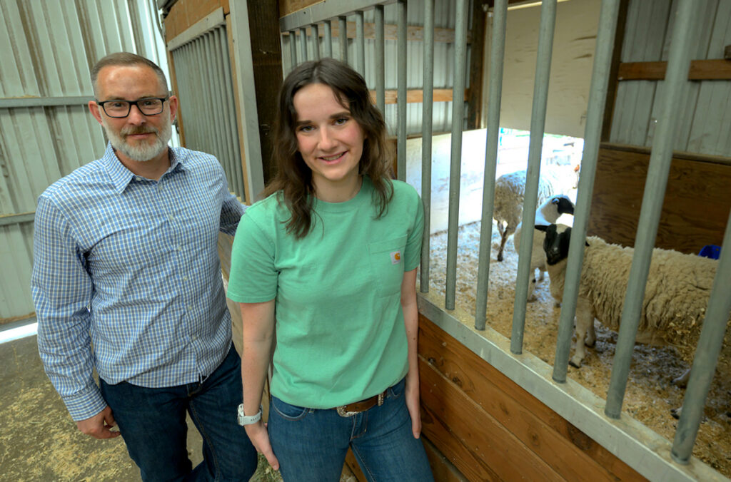 Hanna Meyer and Jon Oatley standing next to a pen filled with sheep.