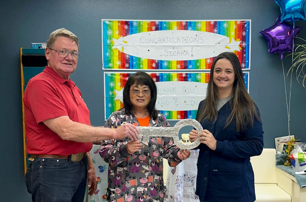 Dr. Roland Hall and his wife Linda hand a large, symbolic key to Dr. Sierra Temple.