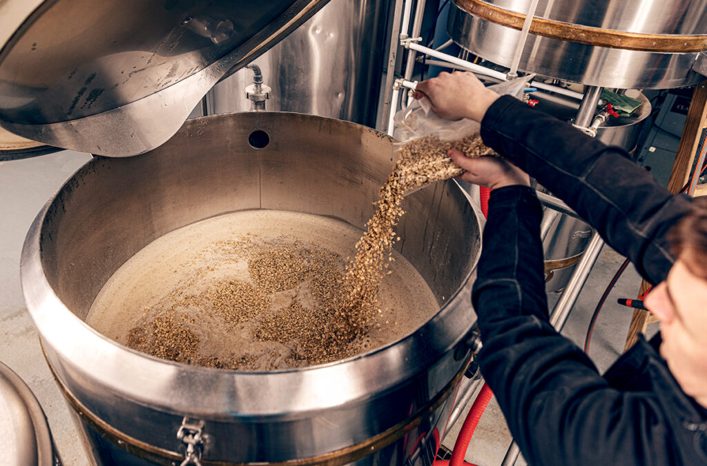 Brewer pouring ingredients into a vat.