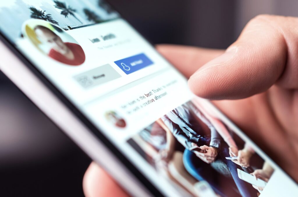 Closeup of a hand scrolling through a social media site on a smartphone.