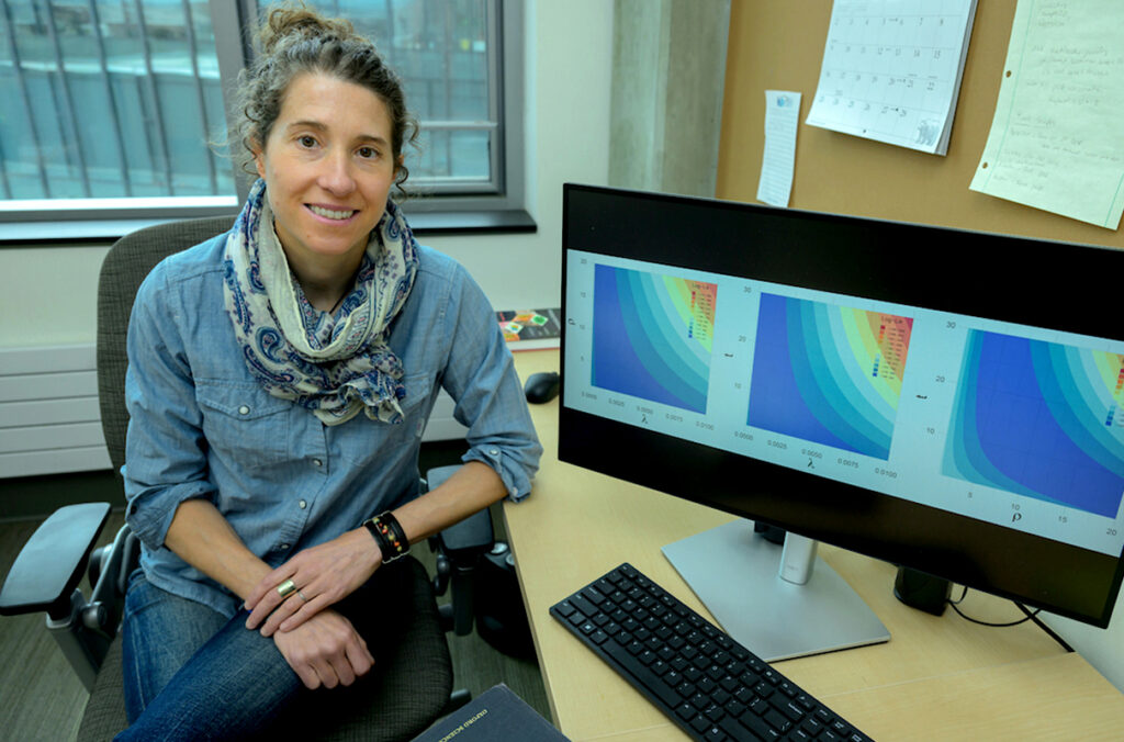 Erin Clancey sitting at a desk in her office, near a computer screen.