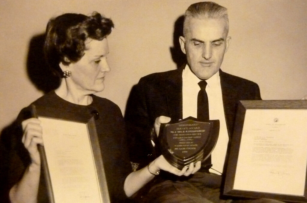 A black and white photo of Hal and Wilma Stellingwerf holding a plaque and two framed letters.