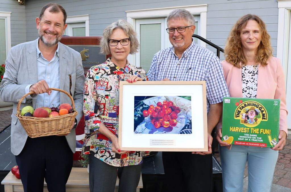 Chris Riley-Tillman and Elizabeth Cantwell accepting regional fruit and farming mementos from Sam Godwin and Ines Hanrahan.
