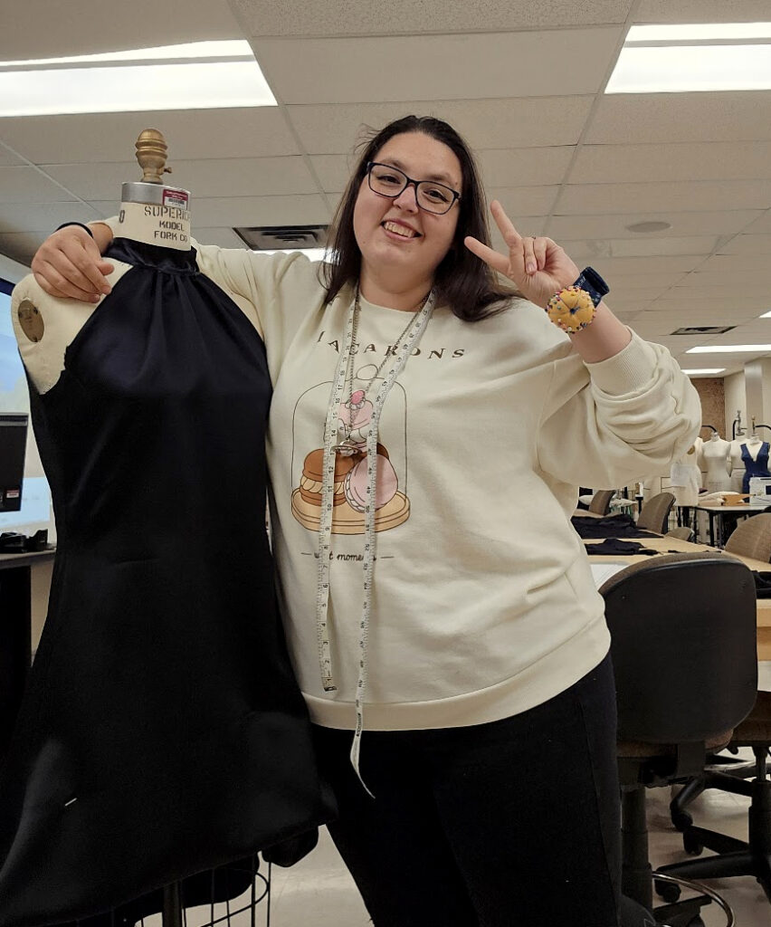 Closeup of Kiah Conway posing next to a mannequin with a dress.