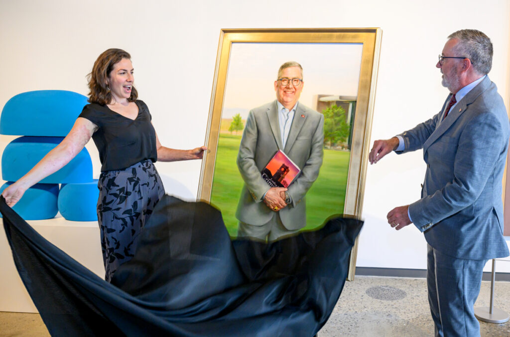 Artist Grace Flott and former WSU President Kirk Schulz unveil a portrait.