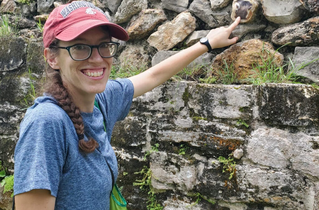 Rachel Horowitz pointing at a stone in a rock wall.
