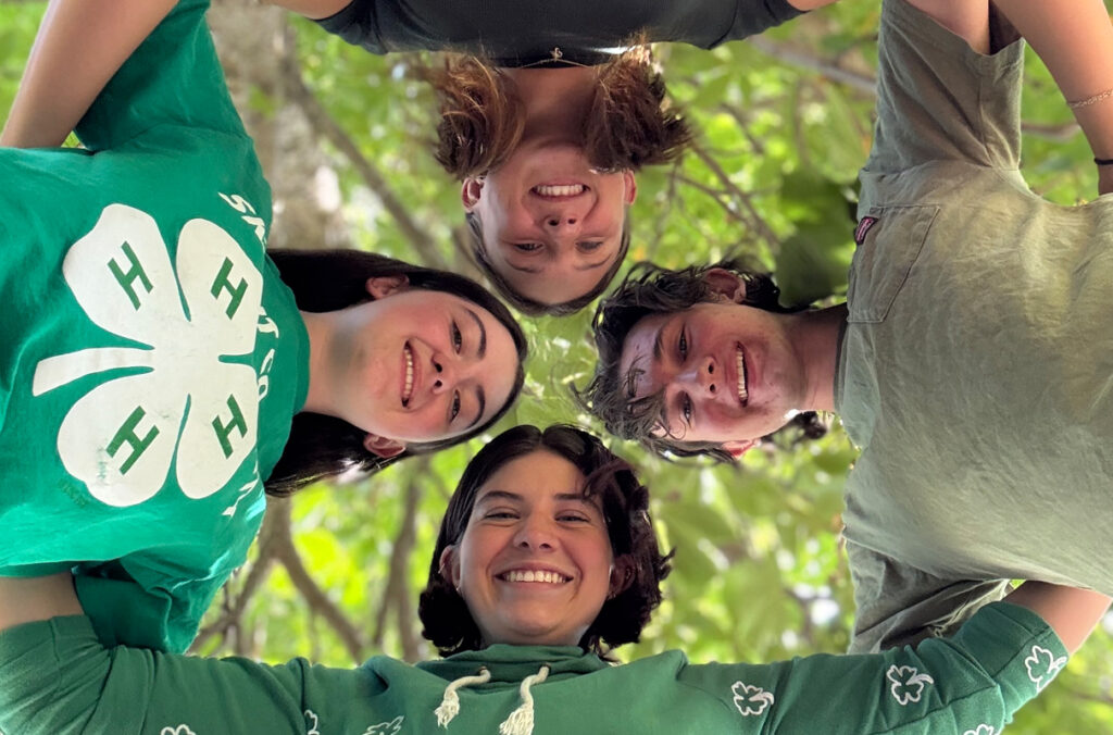 WSU 4-H Club leadership cabinet members huddled in a circle and looking down at a camera.