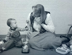 A professor and toddler play with toy landline phones in a black and white photo from 1996.