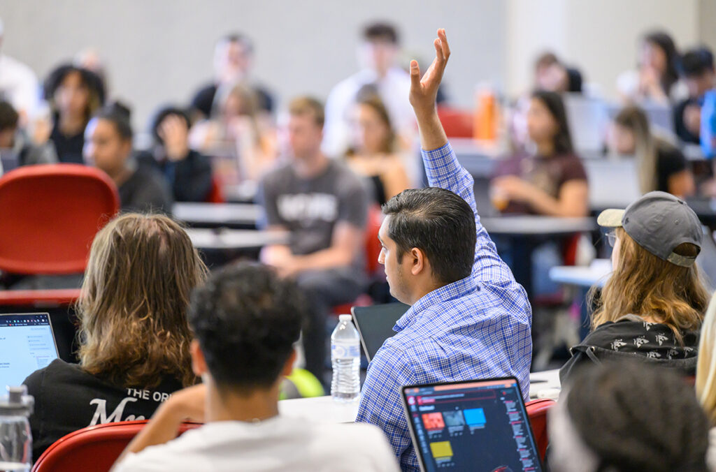 Students raise their hands in a classroom.