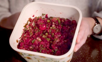 Hands holding a container of cranberry salsa.