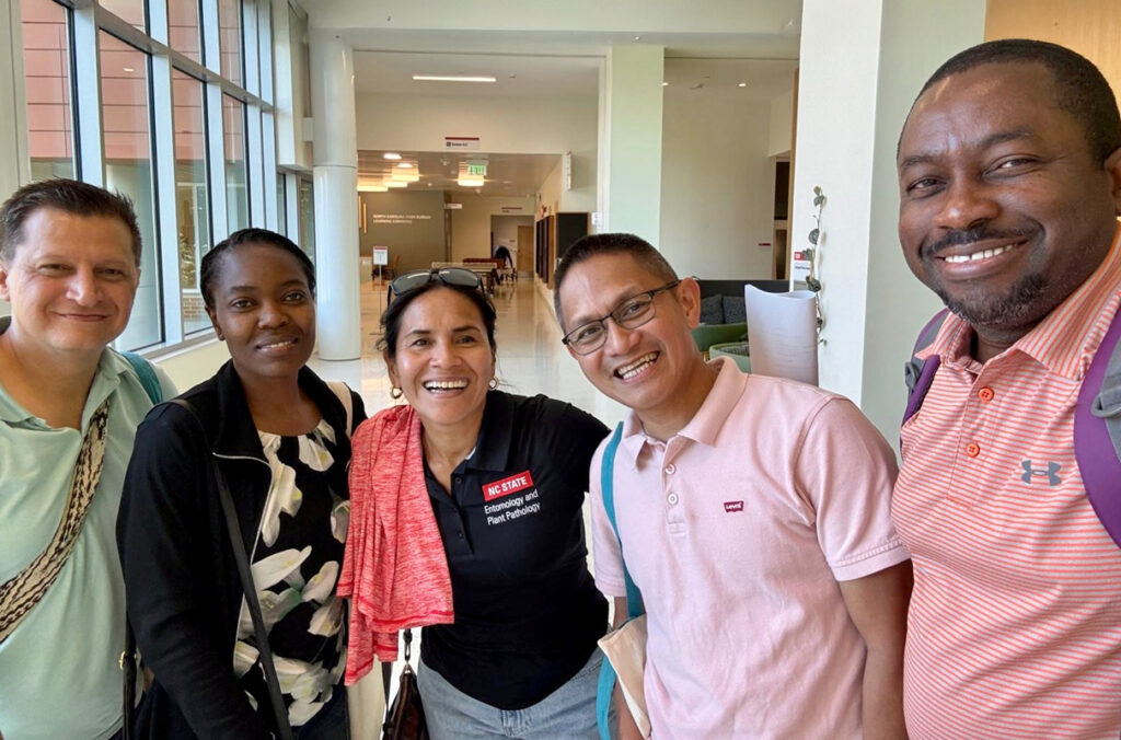 Five plant pathology alumni gathered in a hallway for a group photo.