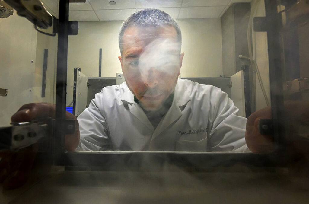 Ryan McLaughlin looking into a clear box used for cannabis vapor research.