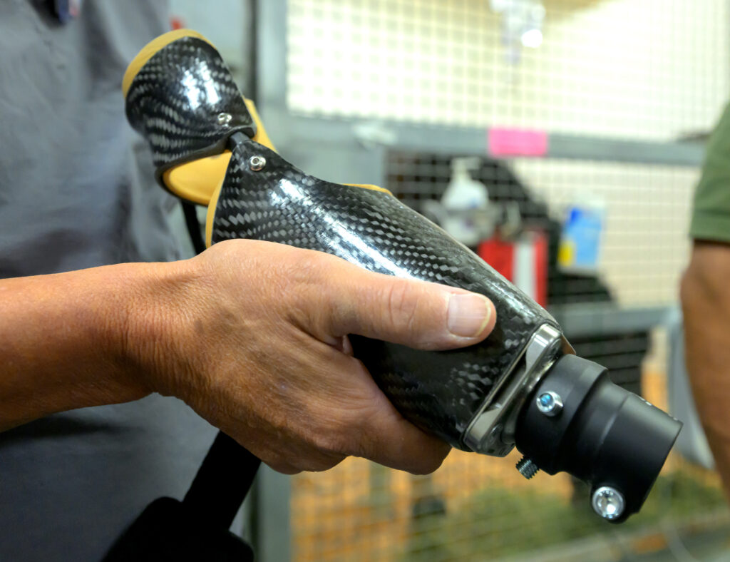 Closeup of a hand holding a custom prosthetic leg for a miniature donkey.