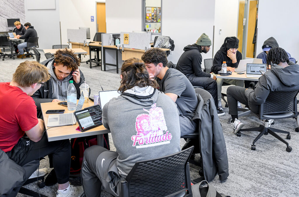 Three groups of student-athletes studying at different tables.