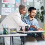 Two people can be seen working collaboratives at a table.