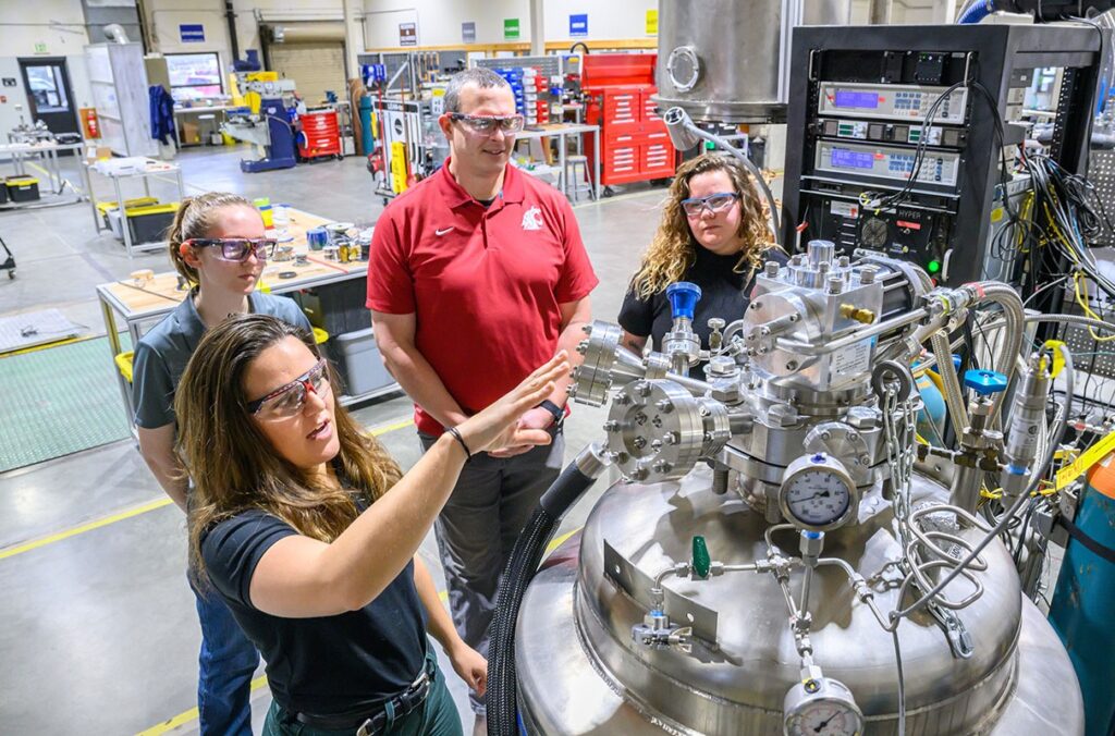 A professor and students look over equipment in a research lab.