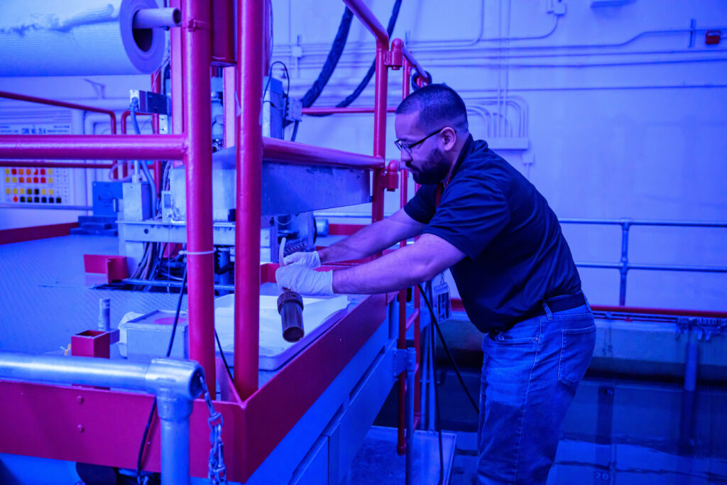 A person working on equipment in a blue-lit nuclear reactor room.