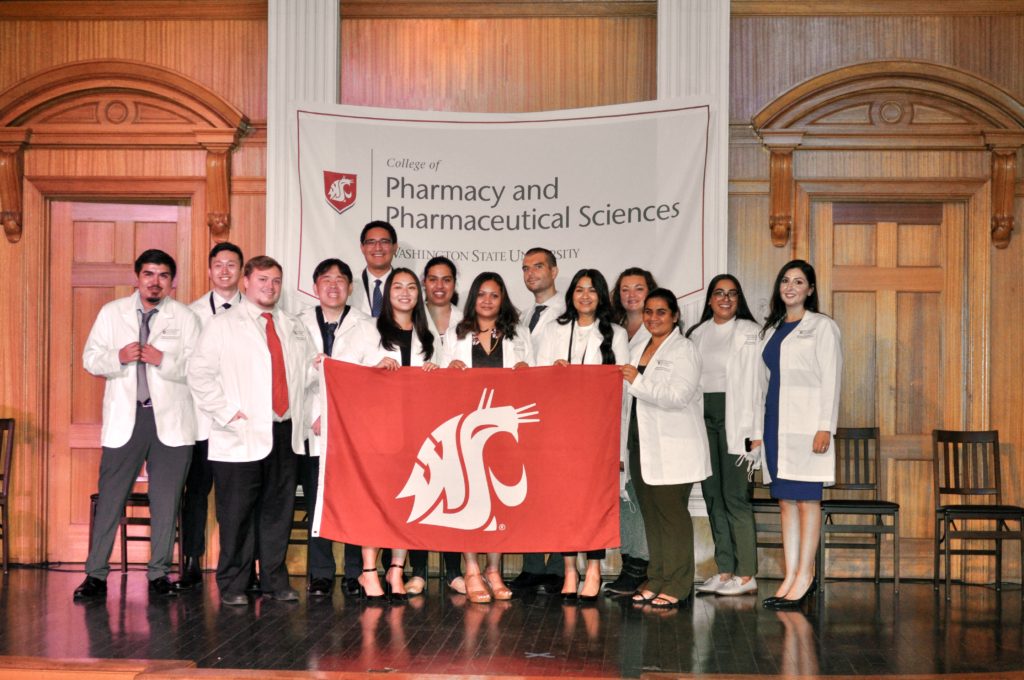 The WSU College of Pharmacy and Pharmaceutical Sciences Yakima Class of 2025 holding a WSU Cougars flag.