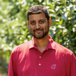 Closeup of Ananth Kalyanaraman standing in an orchard.