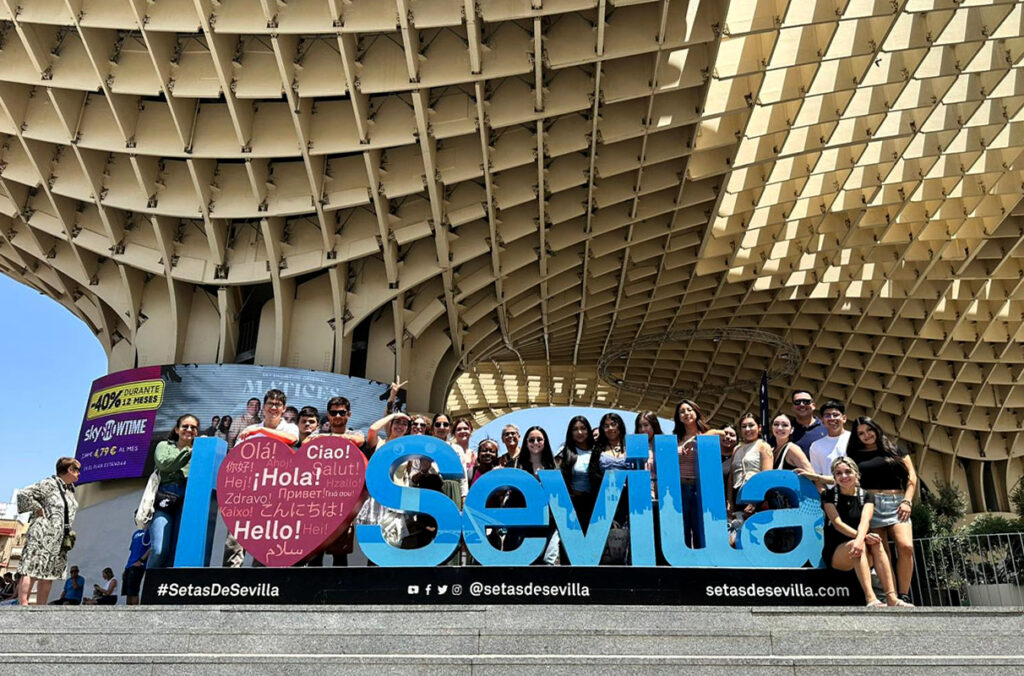 The 2025 First Generation Abroad group poses in front of a sign for Seville, Spain.