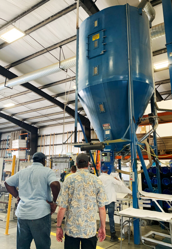 Michael Neff and Lee Gilliam watch as grass seed is processed.